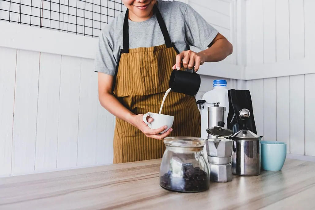Barista Pouring Milk into Coffee