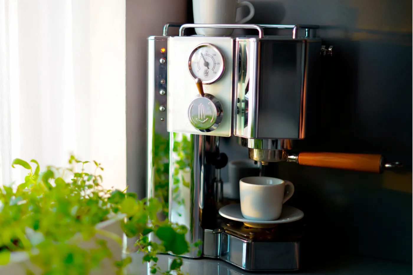 A matte-black drip coffee maker brewing coffee on a wood kitchen counter